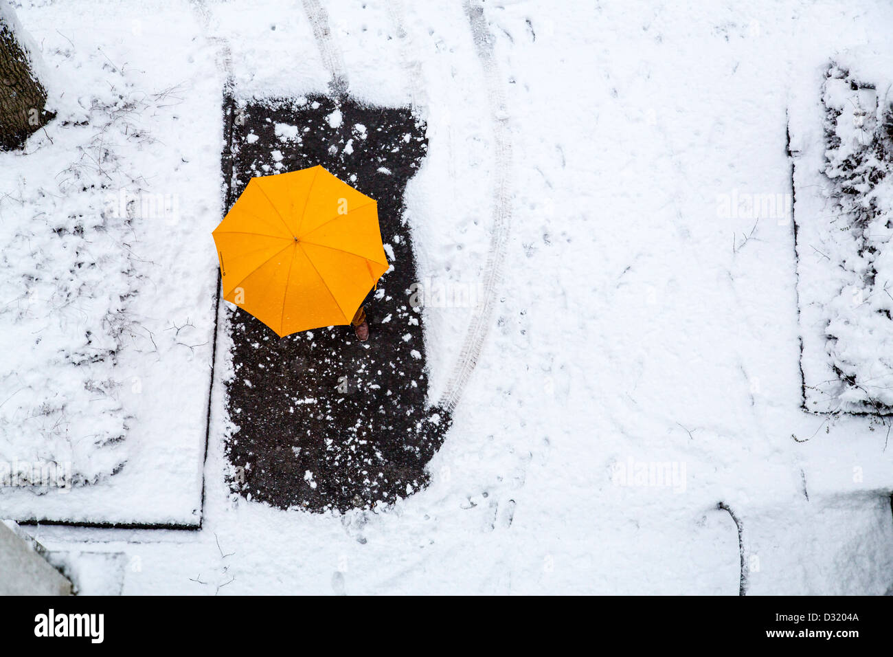 Person with a yellow umbrella walks on a snow covered street. Stock Photo