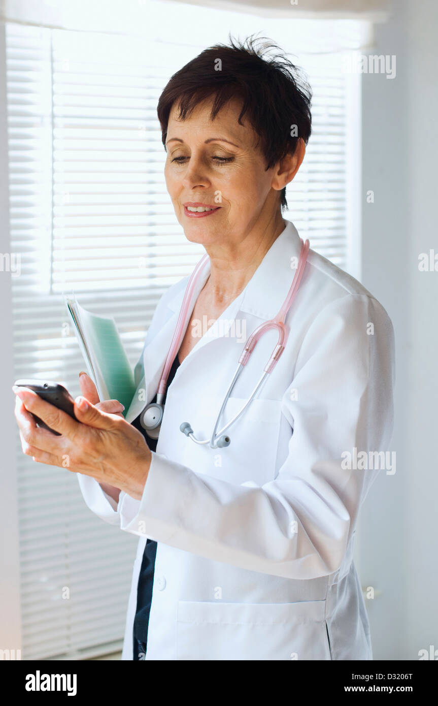 Caucasian doctor using cell phone in office Stock Photo