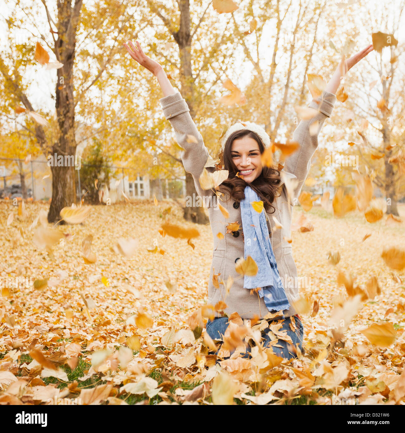 Caucasian woman playing in autumn leaves Stock Photo
