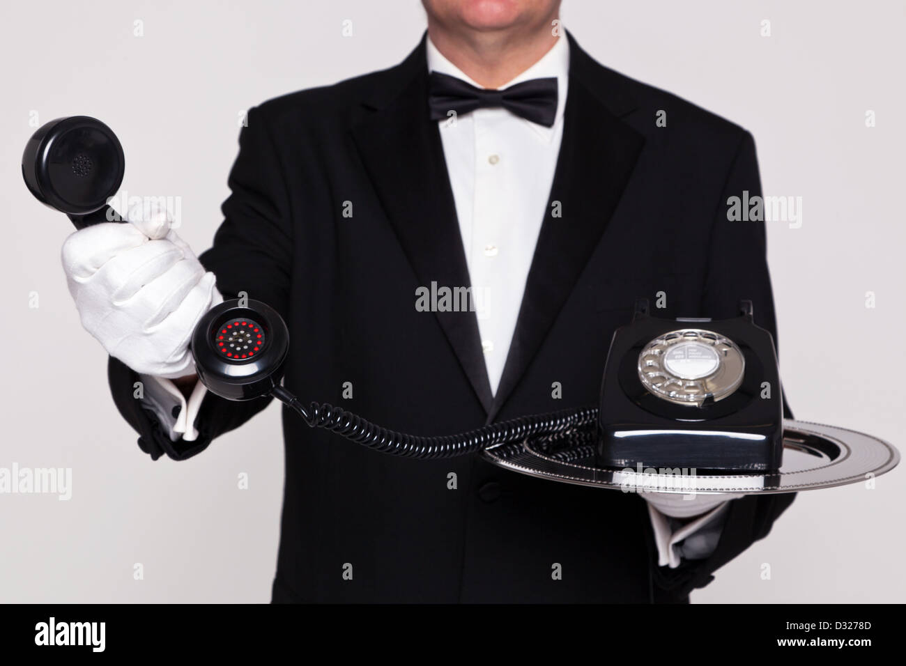 Butler handing you the receiver from a retro telephone upon a silver serving tray. Stock Photo