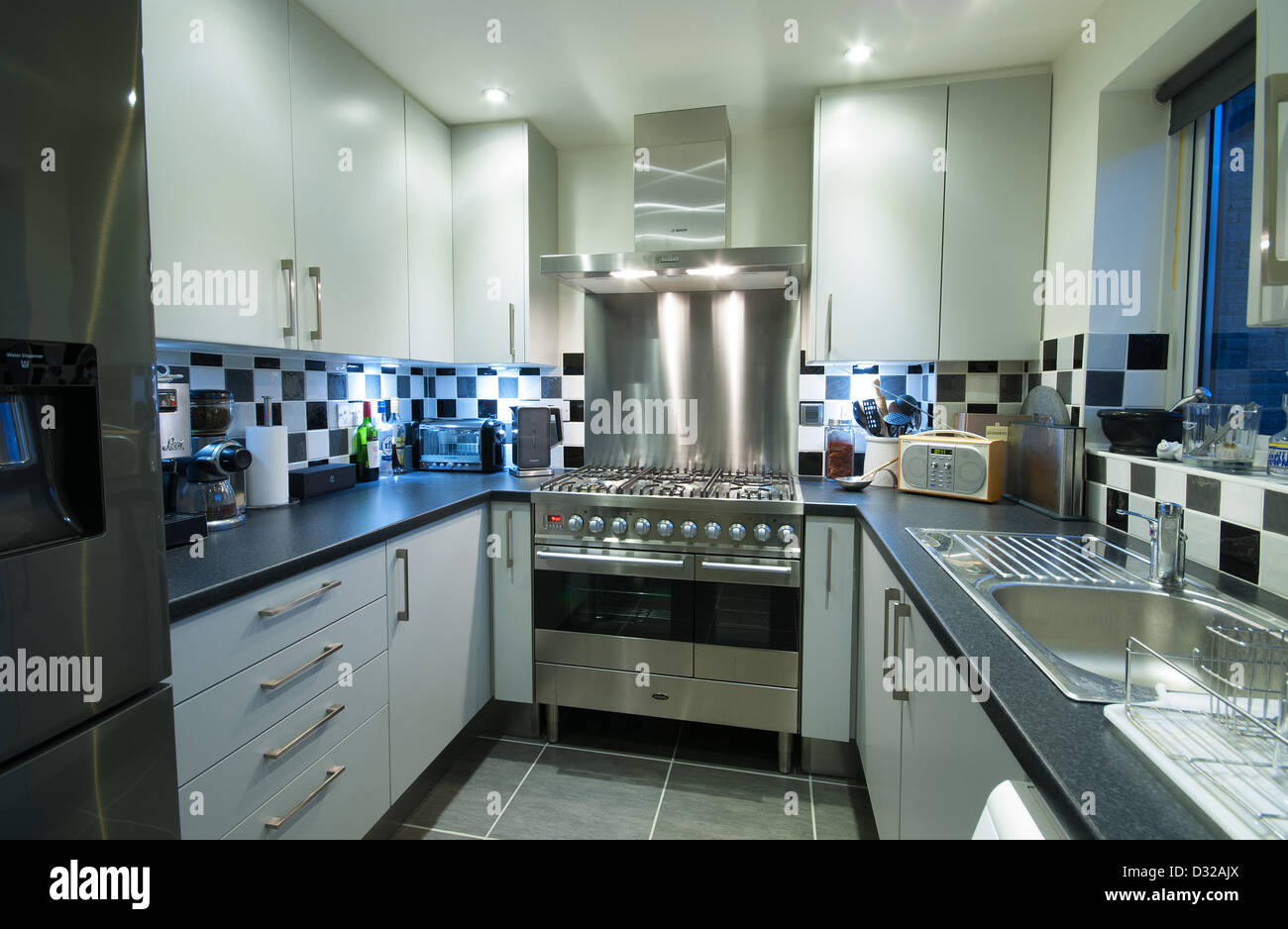 A small, modern domestic kitchen with a range cooker and lots of storage space. UK, 2013. Stock Photo