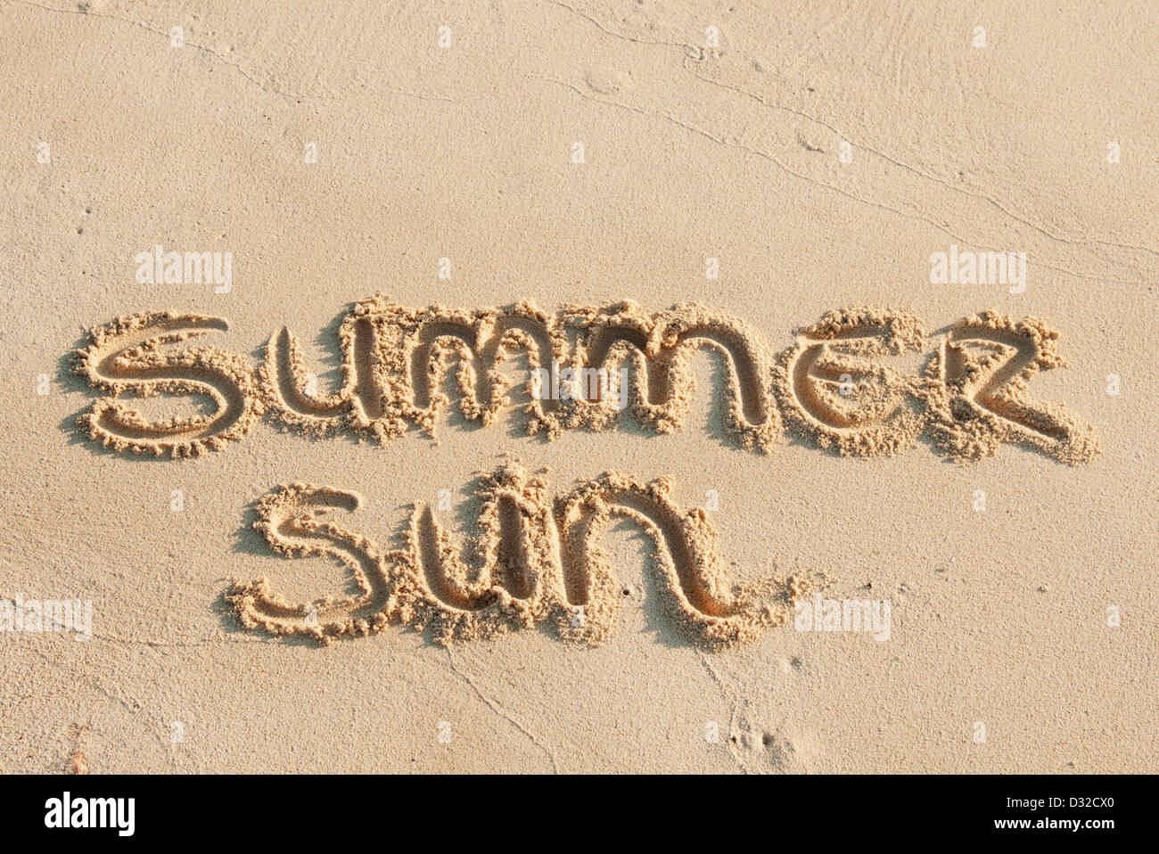 summer sun written in the sand on a beach Stock Photo