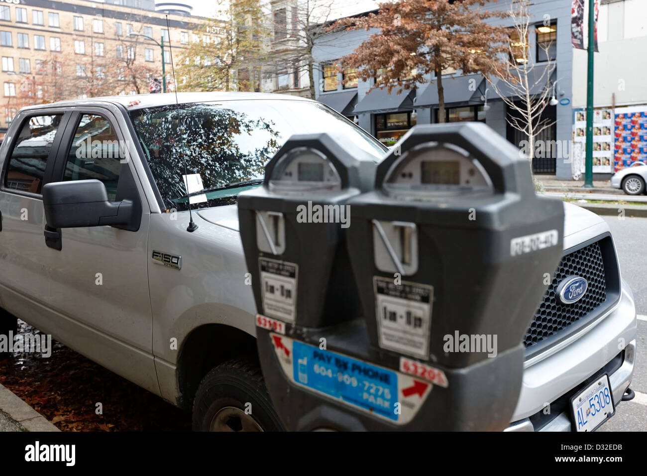 vehicle with parking ticket parked onstreet beside expired parking meter Vancouver BC Canada Stock Photo