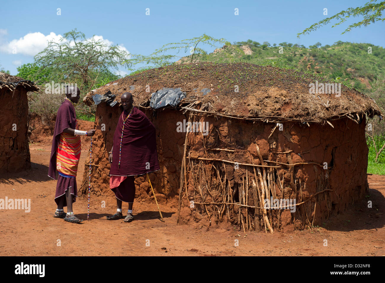 Maasai men and traditional huts in the manyatta, Kenya Stock Photo