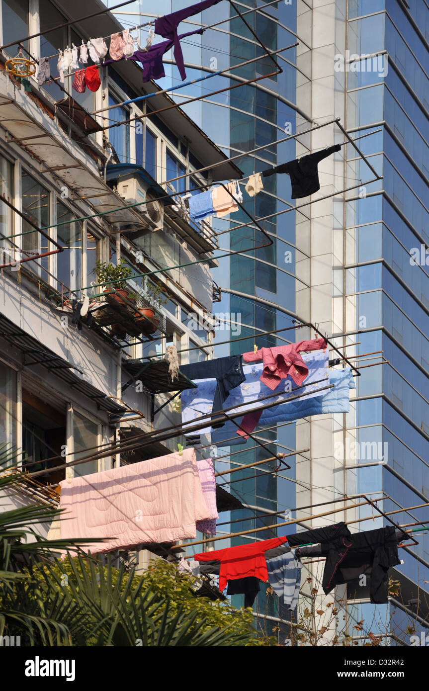 House with laundry hanging from the windows on bamboo sticks in a street of Shanghai, modern tower in the background  - China Stock Photo