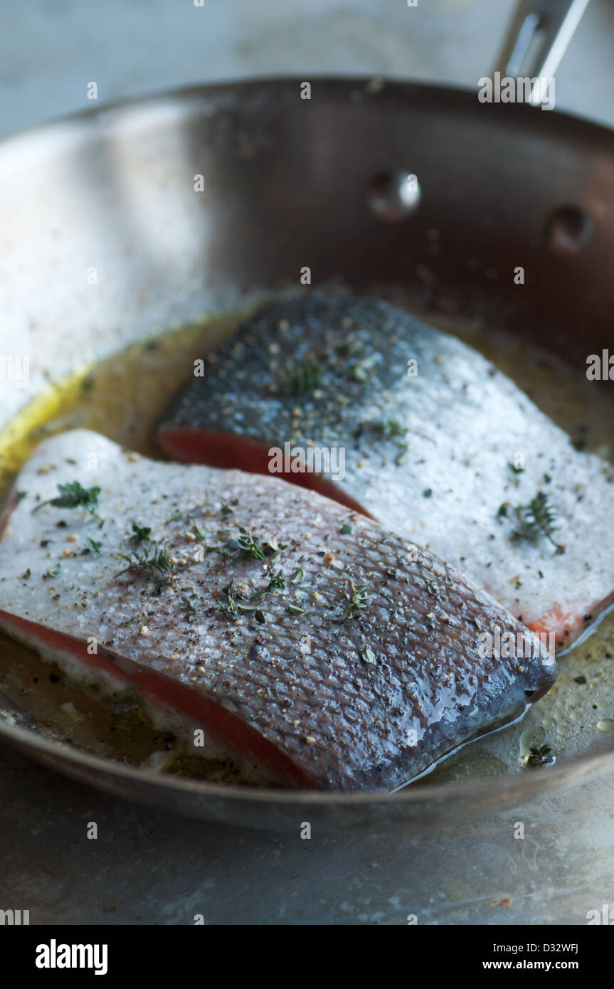 Fresh seasoned salmon fillets cooking in stainless saute pan Stock Photo