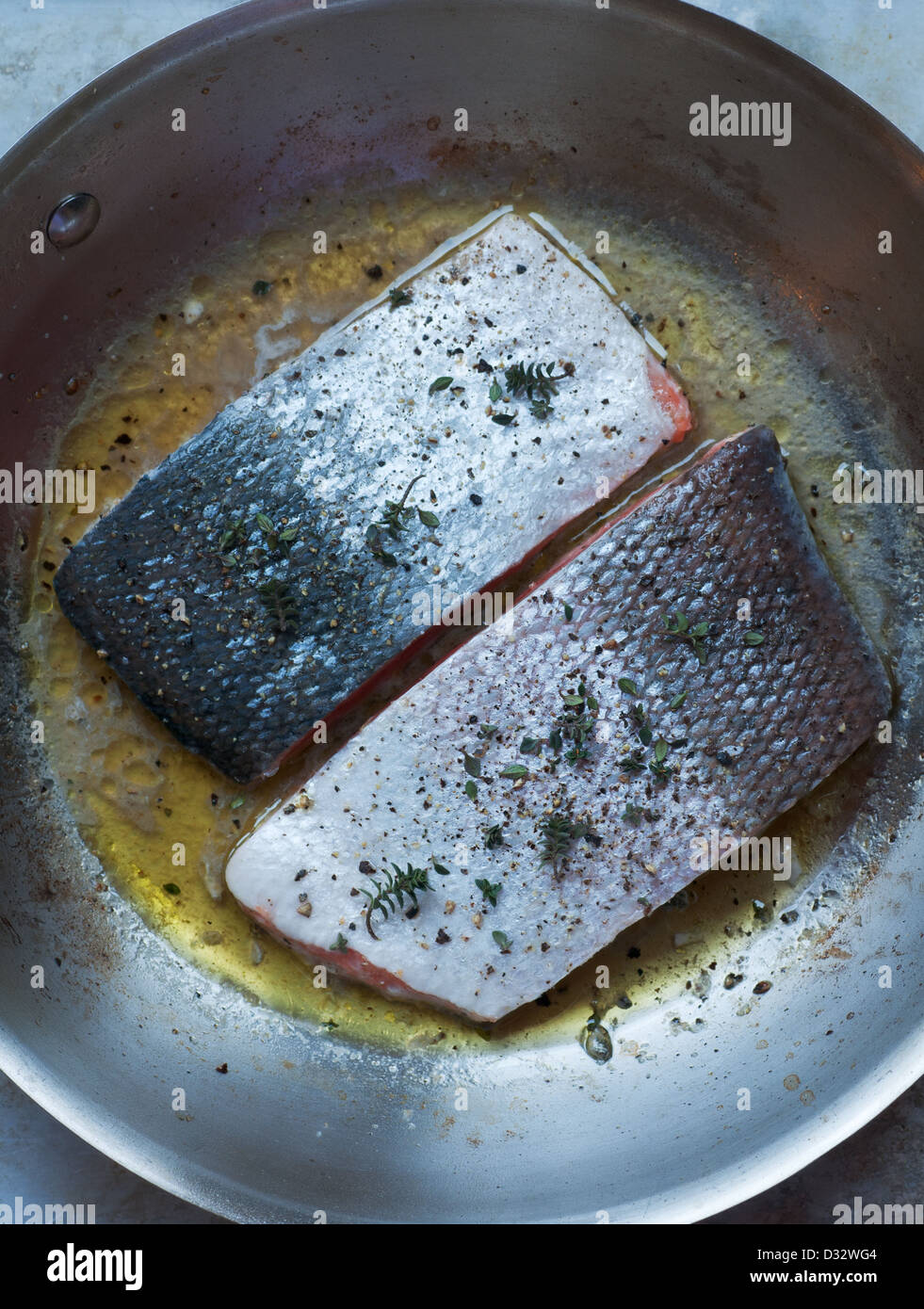 Fresh seasoned salmon fillets cooking in stainless saute pan Stock Photo