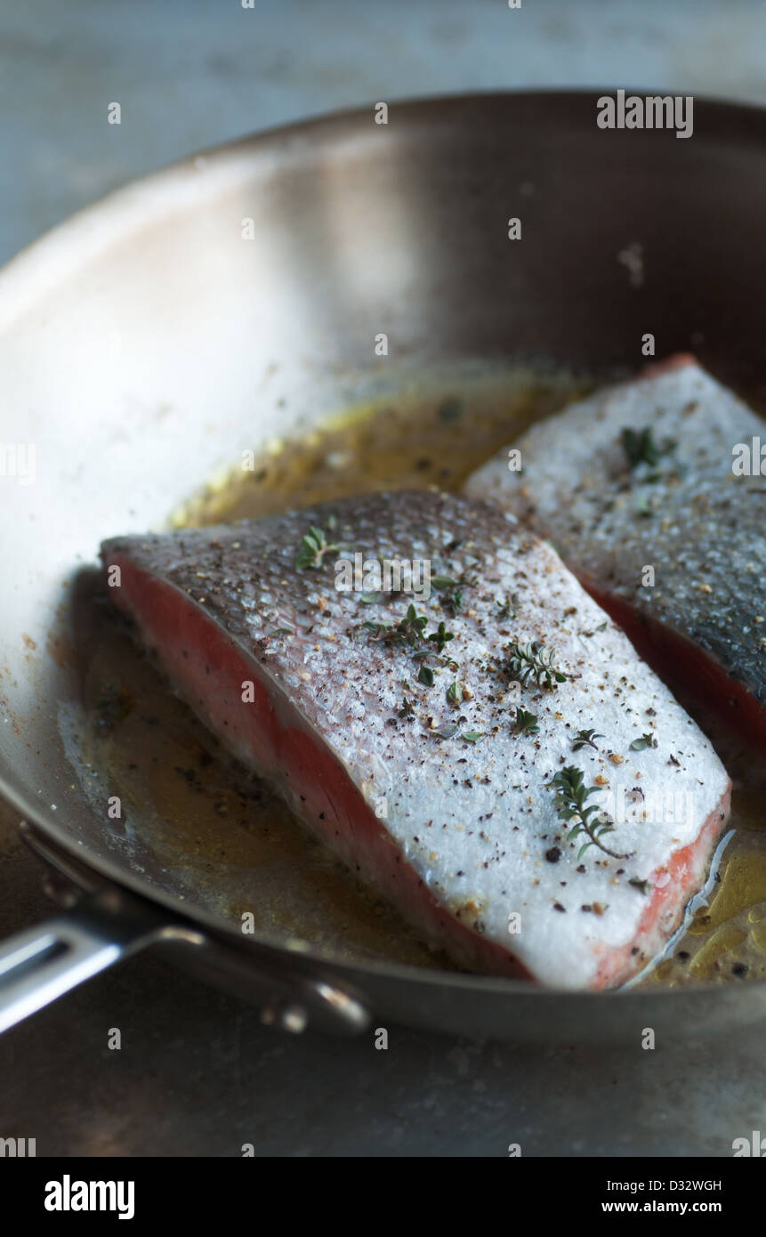 Fresh seasoned salmon fillets cooking in stainless saute pan Stock Photo