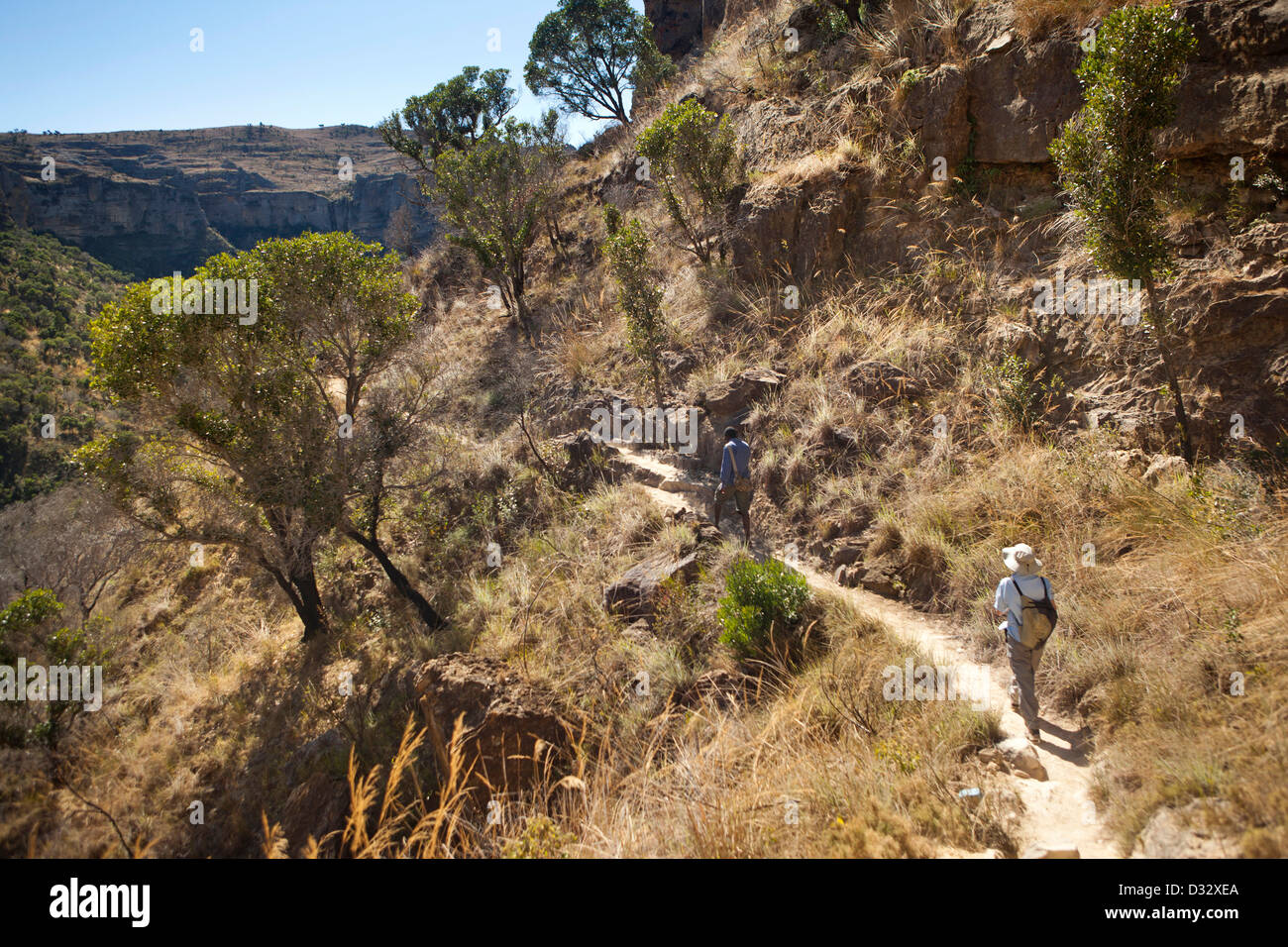 Madagascar, Parc National de l’Isalo, Namaza, tourist and guide walking down rocky trail Stock Photo