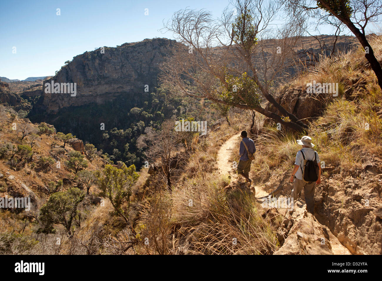 Madagascar, Parc National de l’Isalo, Namaza, tourist and guide walking down rocky trail Stock Photo