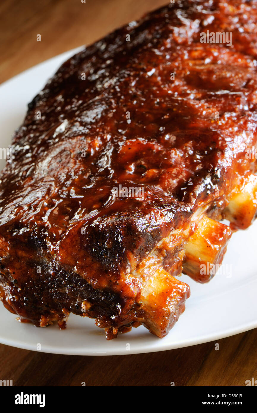 Grilled juicy barbecue pork ribs in a white plate, selective focus. Stock Photo