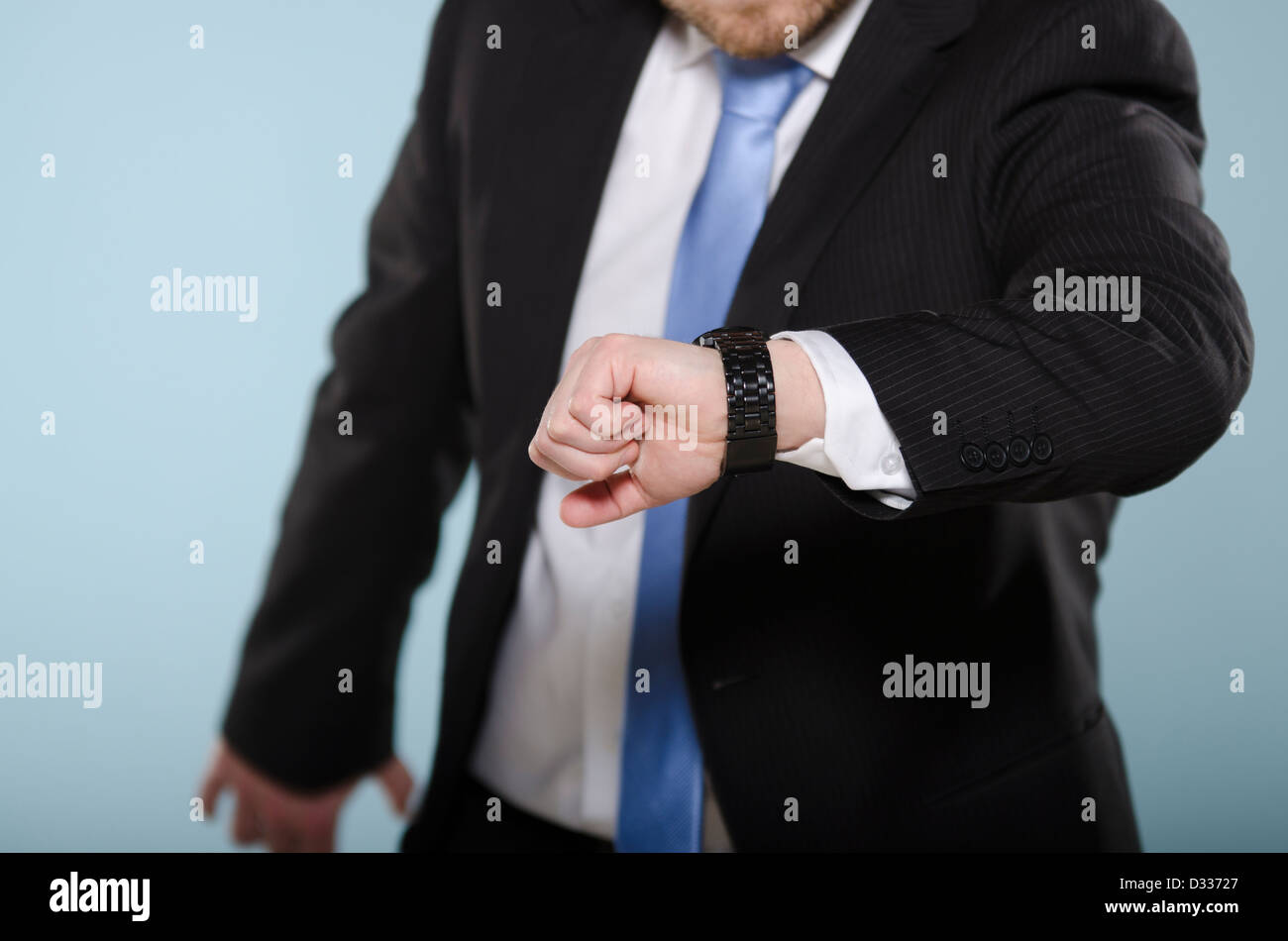 Businessman in hurry watching his clock. Middle section of casually suited man moving and checking time from his watch. Stock Photo