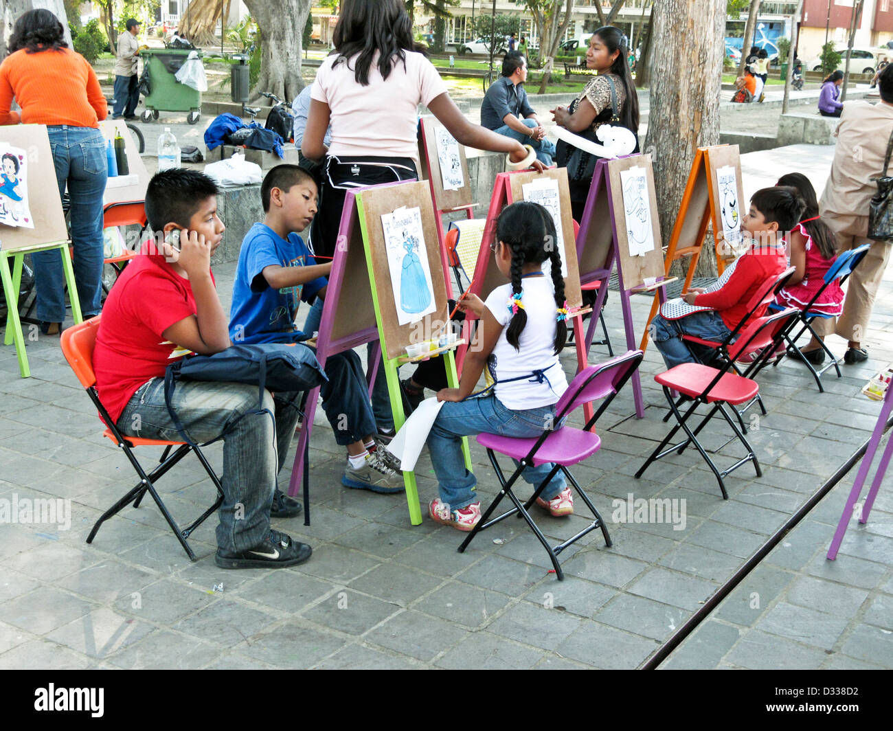 Mexican kids children working at brightly colored miniature easels participate in outdoor art class Llano park Oaxaca Mexico Stock Photo