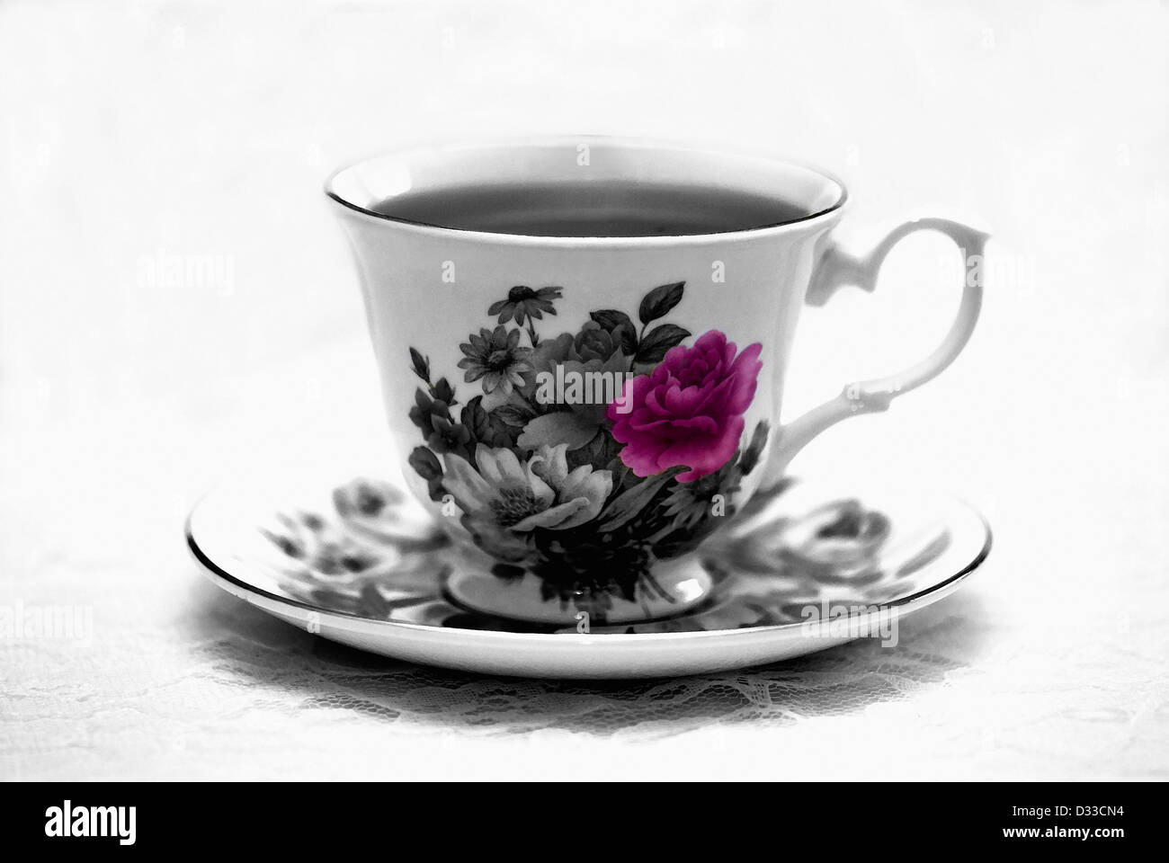 A cup of coffee in a china floral cup and saucer, resting on a lace tablecloth. Selective color. Conceptual image. Stock Photo