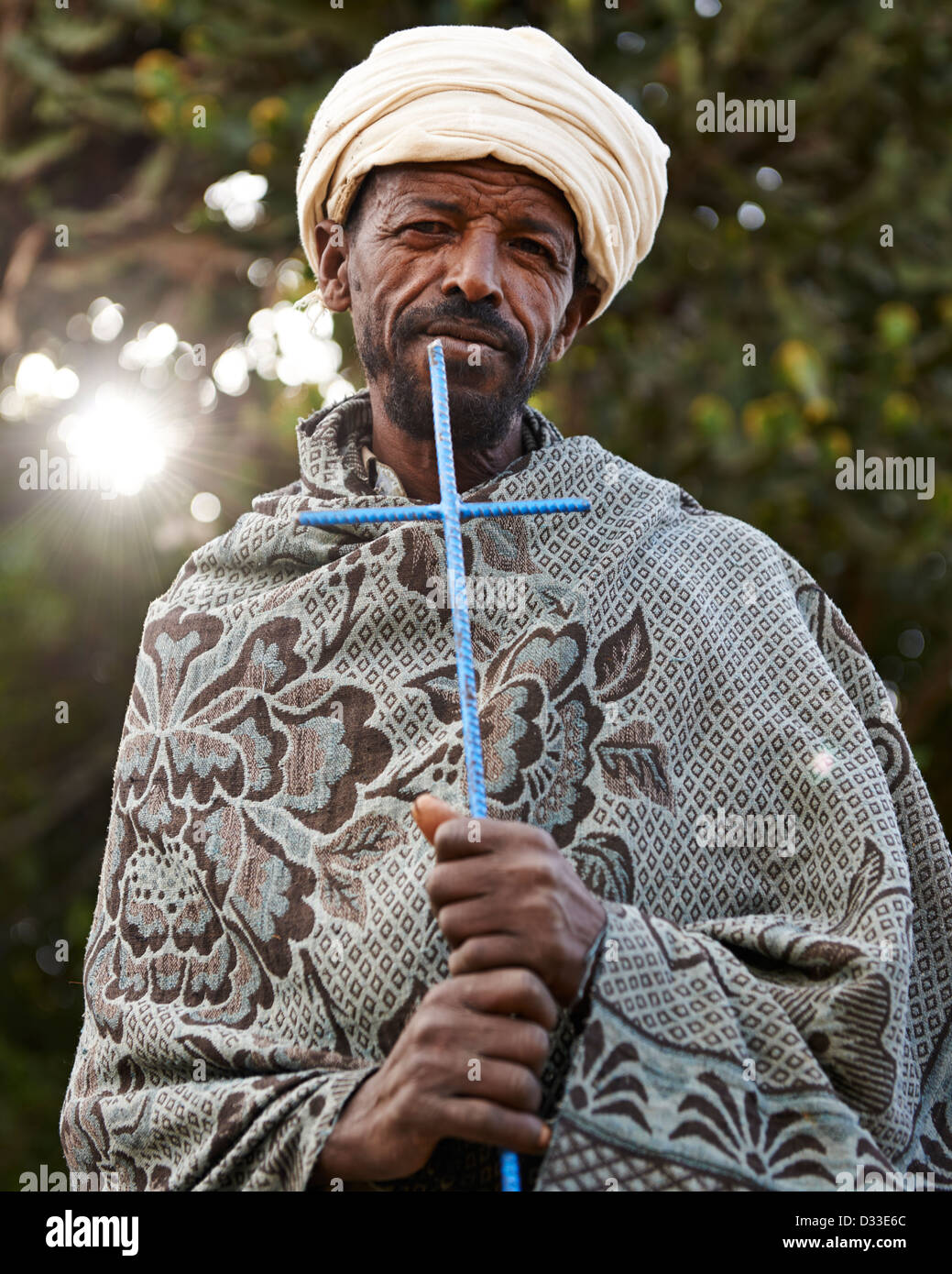 A elder local pilgrim man carrying a blue cross and standing in front of a forest Stock Photo