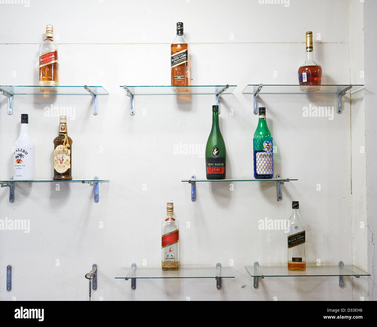 Various bottles of alcohol on glass shelves on a wall Stock Photo Alamy