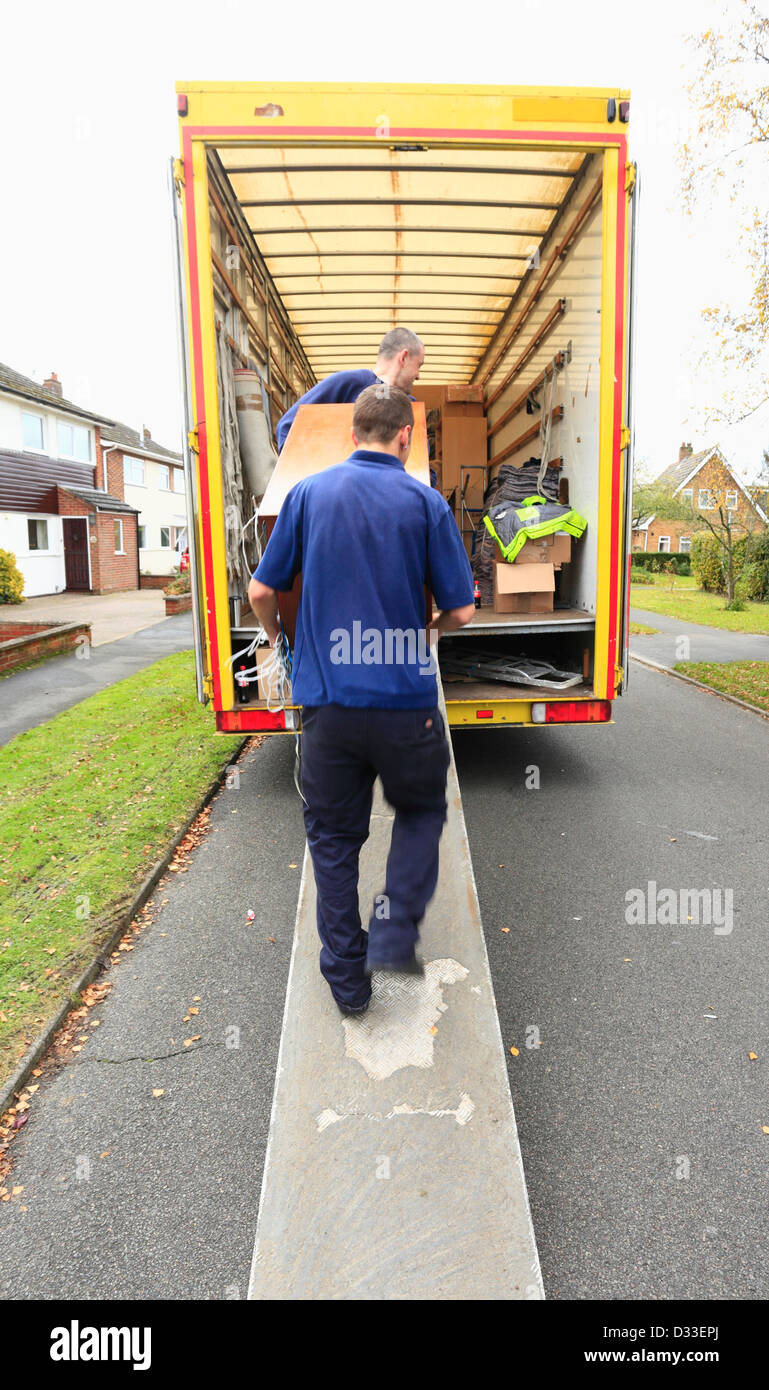 Removal men carrying furniture into a removal van. Stock Photo