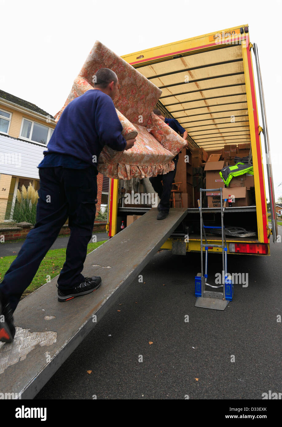 Removal men carrying furniture into a removal van. Stock Photo