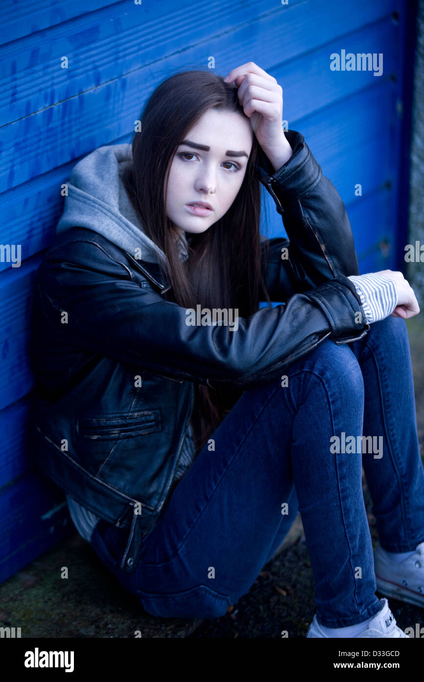 A troubled young teenage girl sitting outside. Stock Photo