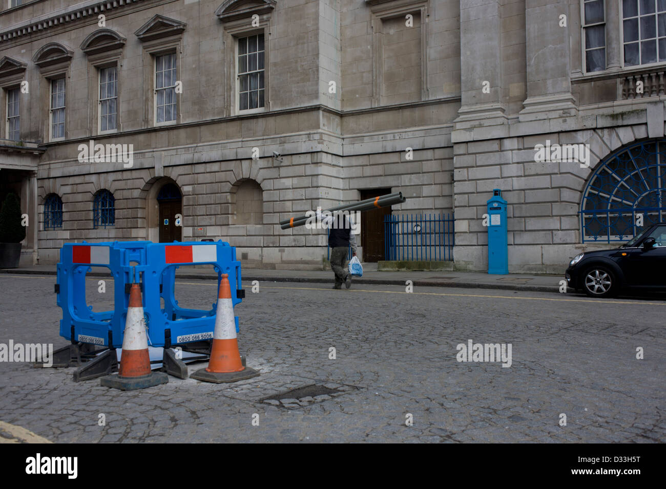 A blue-themed street landscape of a safety fencing, a blue police box and a rider on a blue Boris bike outside Mansion House in the City of London. Stock Photo