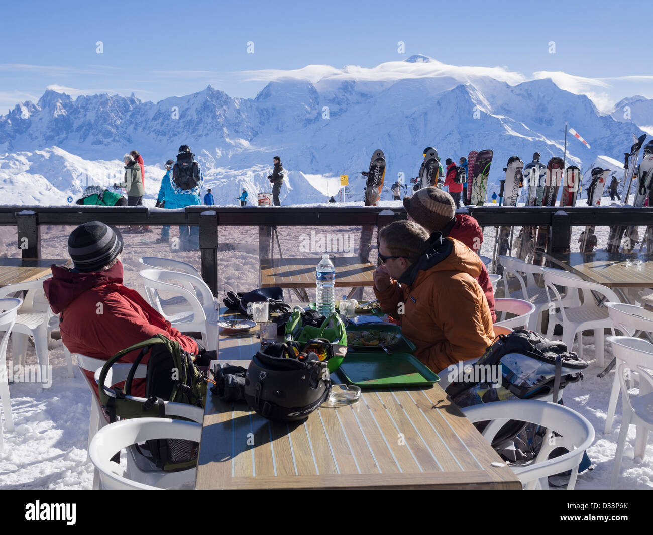 People skiers sitting outside Les Grandes Platieres mountain restaurant in Le Grand Massif ski area with view to Mont Blanc in French Alps, France Stock Photo