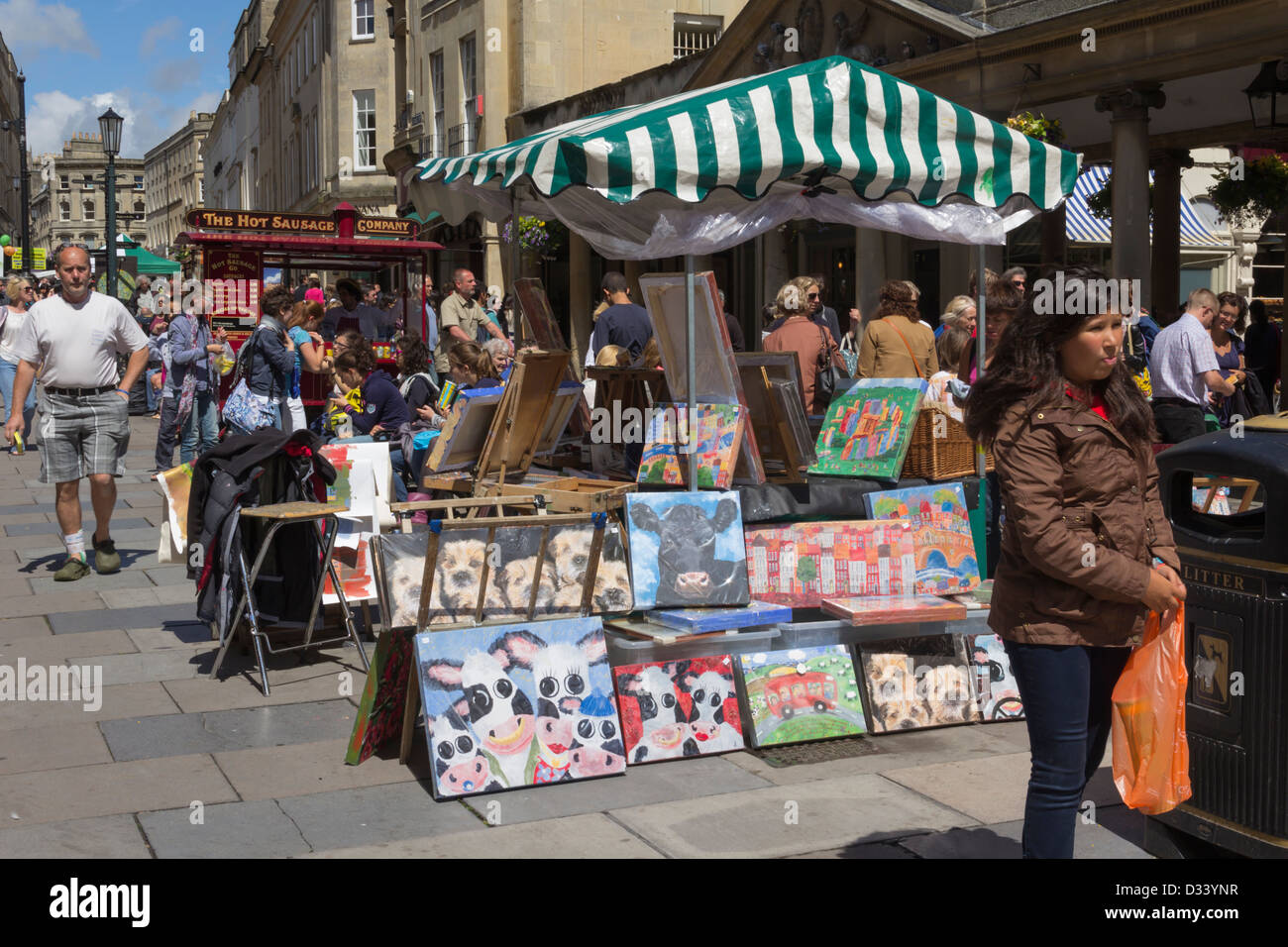 An artists stall selling apparently original paintings adjacent to the Roman Baths on Stall Street in Bath. Stock Photo