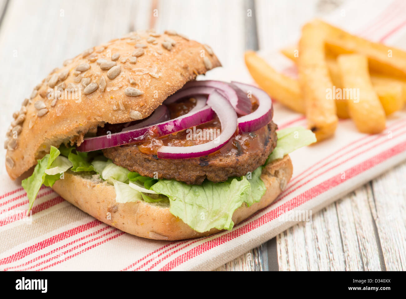 A veggie burger with red onion, lettuce, and relish in a bread bun served with a side of French