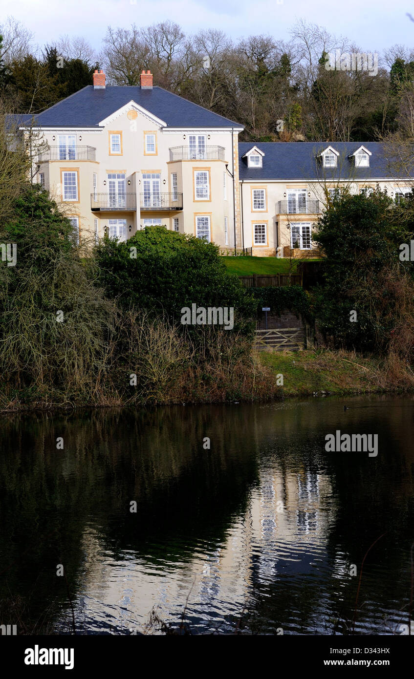 Two and three storey newly built domestic houses built in a Victorian style and over looking a large pond or lake. Stock Photo
