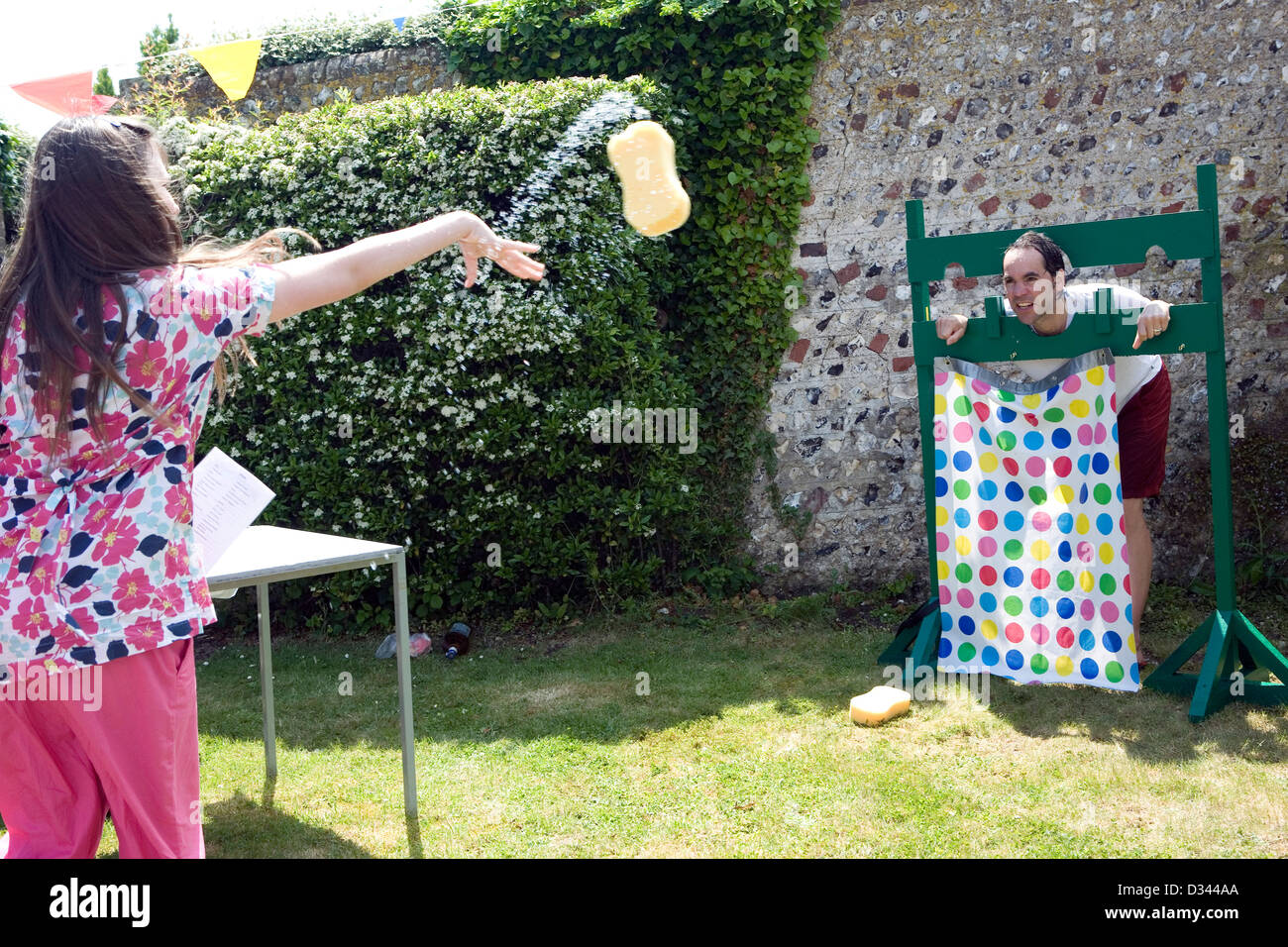 A teacher has wet sponges thrown at him as he stands in a medieval stock at an English summer fair. Stock Photo