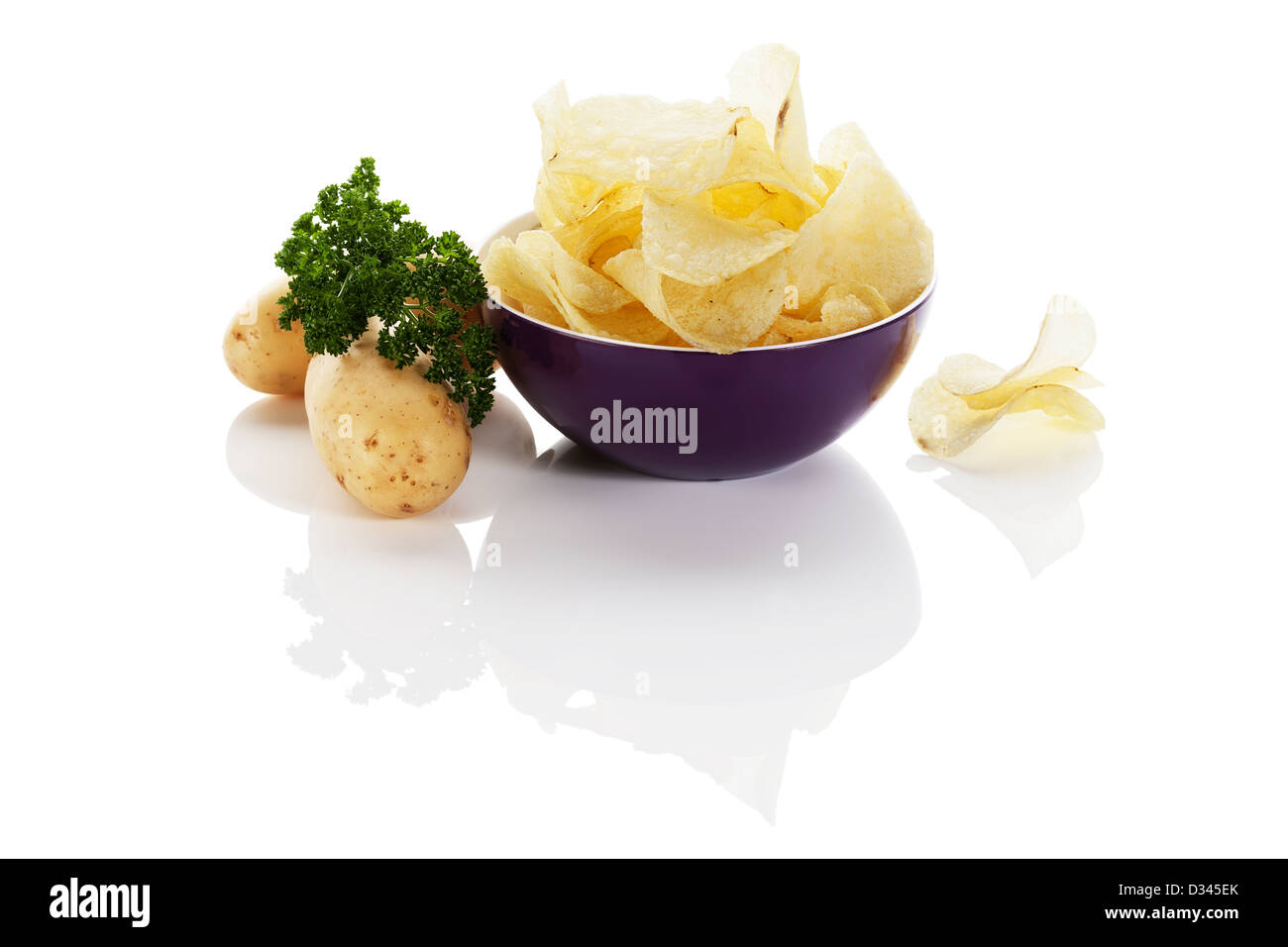 potato chips in a purple small bowl with potatoes aside on white background Stock Photo
