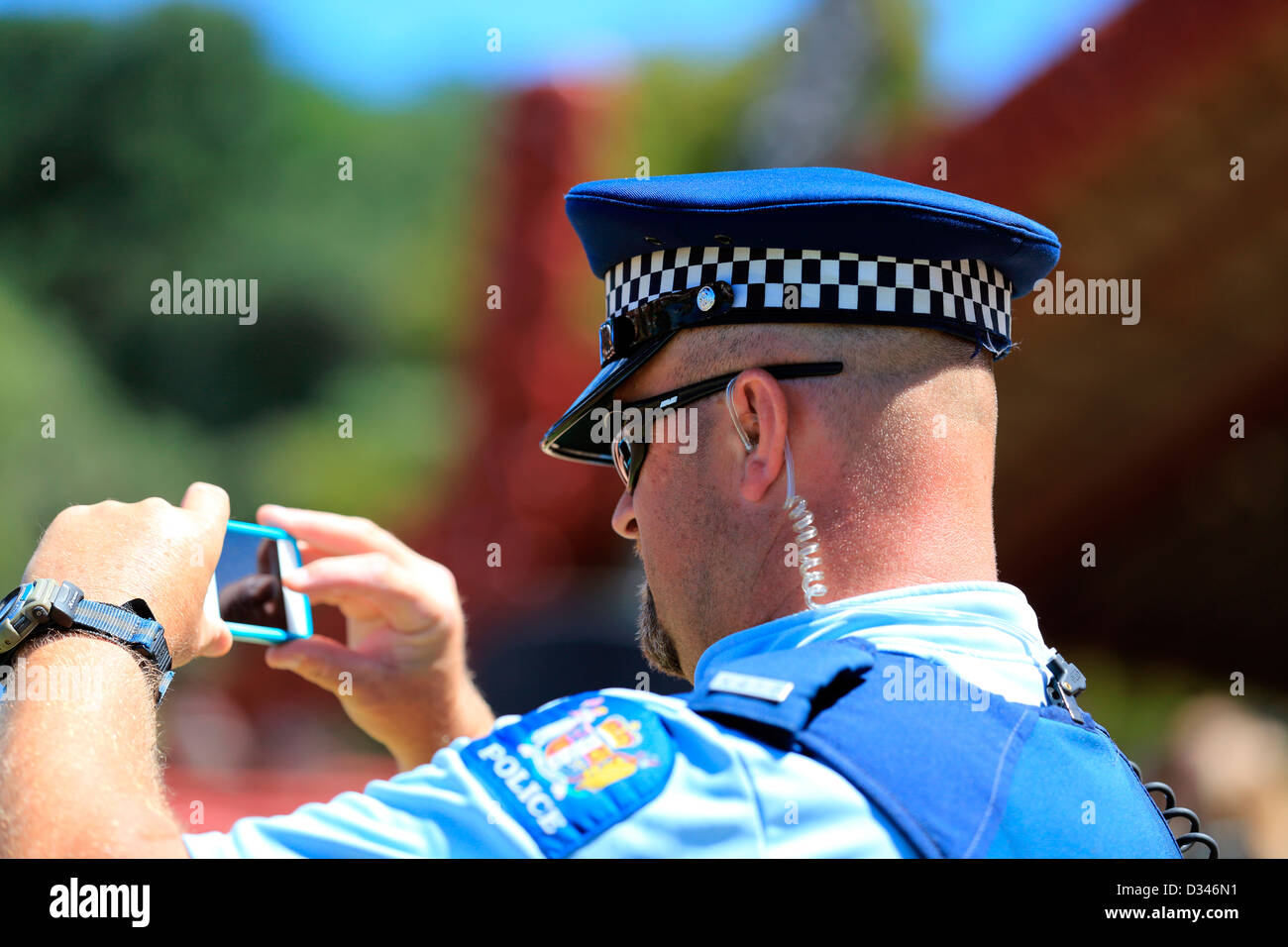 A New Zealand police officer takes a photo of a group of people during Waitangi Day celebrations Stock Photo