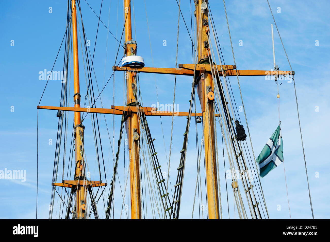 Masts on a tall ship moored in harbour against a blue sky. Stock Photo