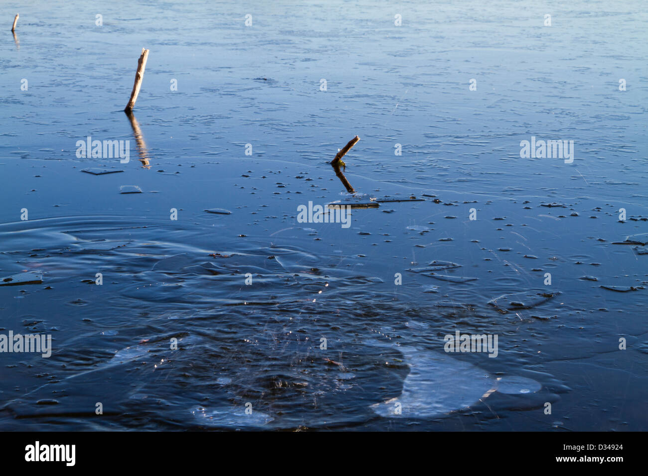 Rock falling through ice into a lake Stock Photo