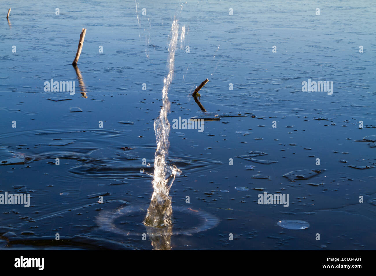 Rock falling through ice into a lake Stock Photo
