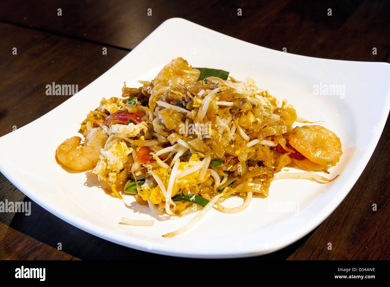 Plate of Penang Fried Kway Teow Noodles with Prawns Chinese Sausage Eggs Green Chives and Bean Sprouts Stock Photo