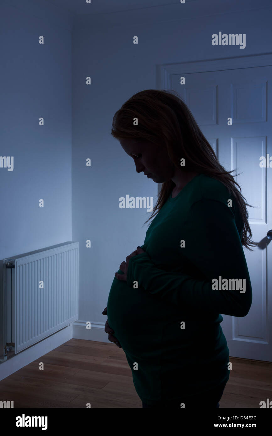 Young pregnant woman silhouetted at home. Stock Photo