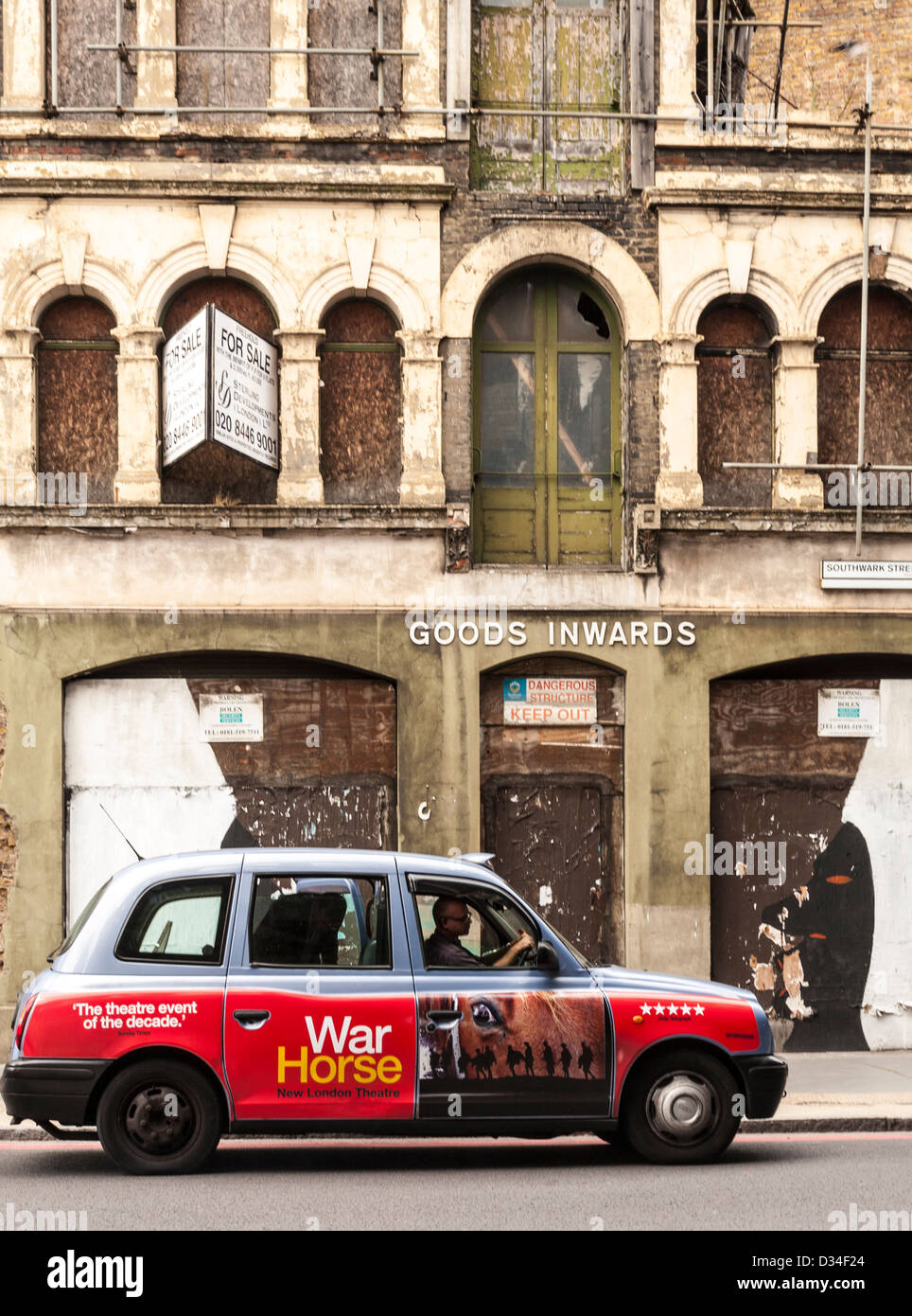 London cab driving in front of delapidated building, London, UK Stock Photo