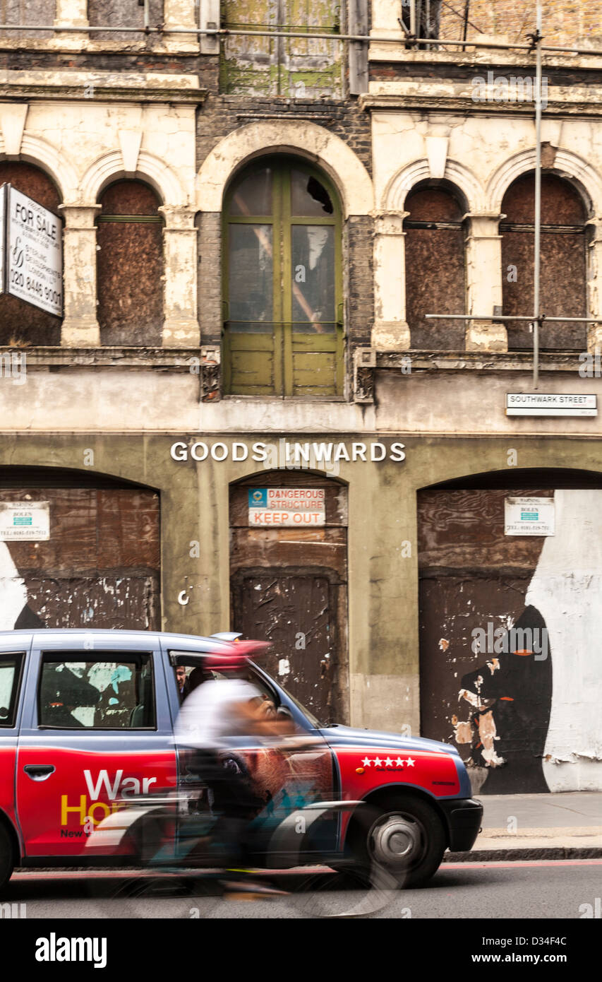 London cab driving in front of delapidated building, London, UK Stock Photo