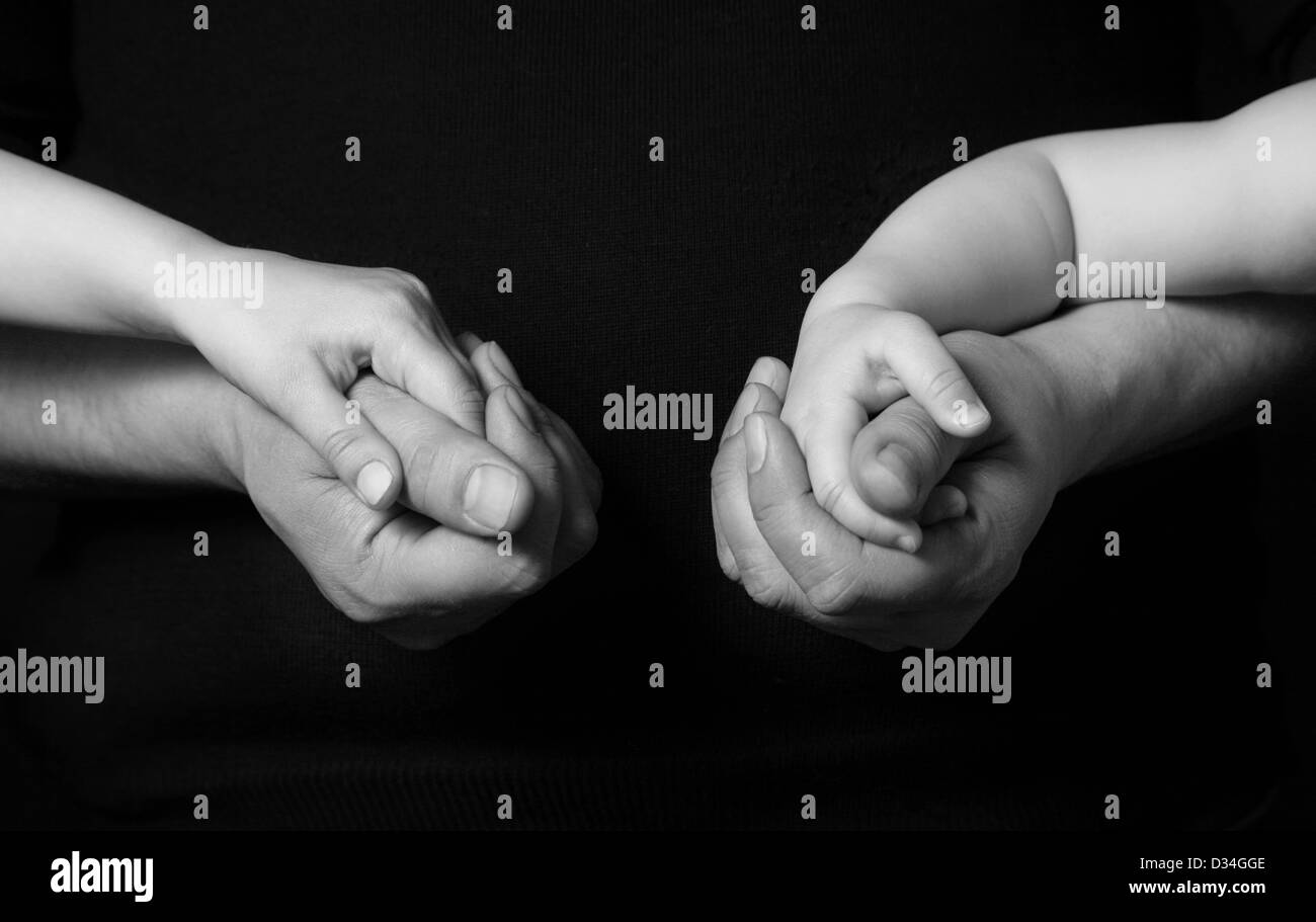Hands of the father and his daughters on a dark background Stock Photo