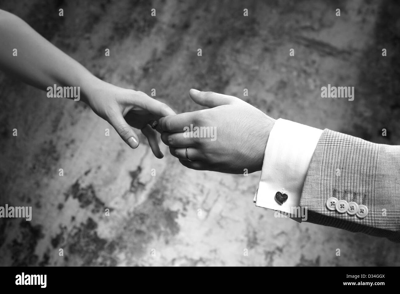 Female hands in man's hands on old wall background Stock Photo