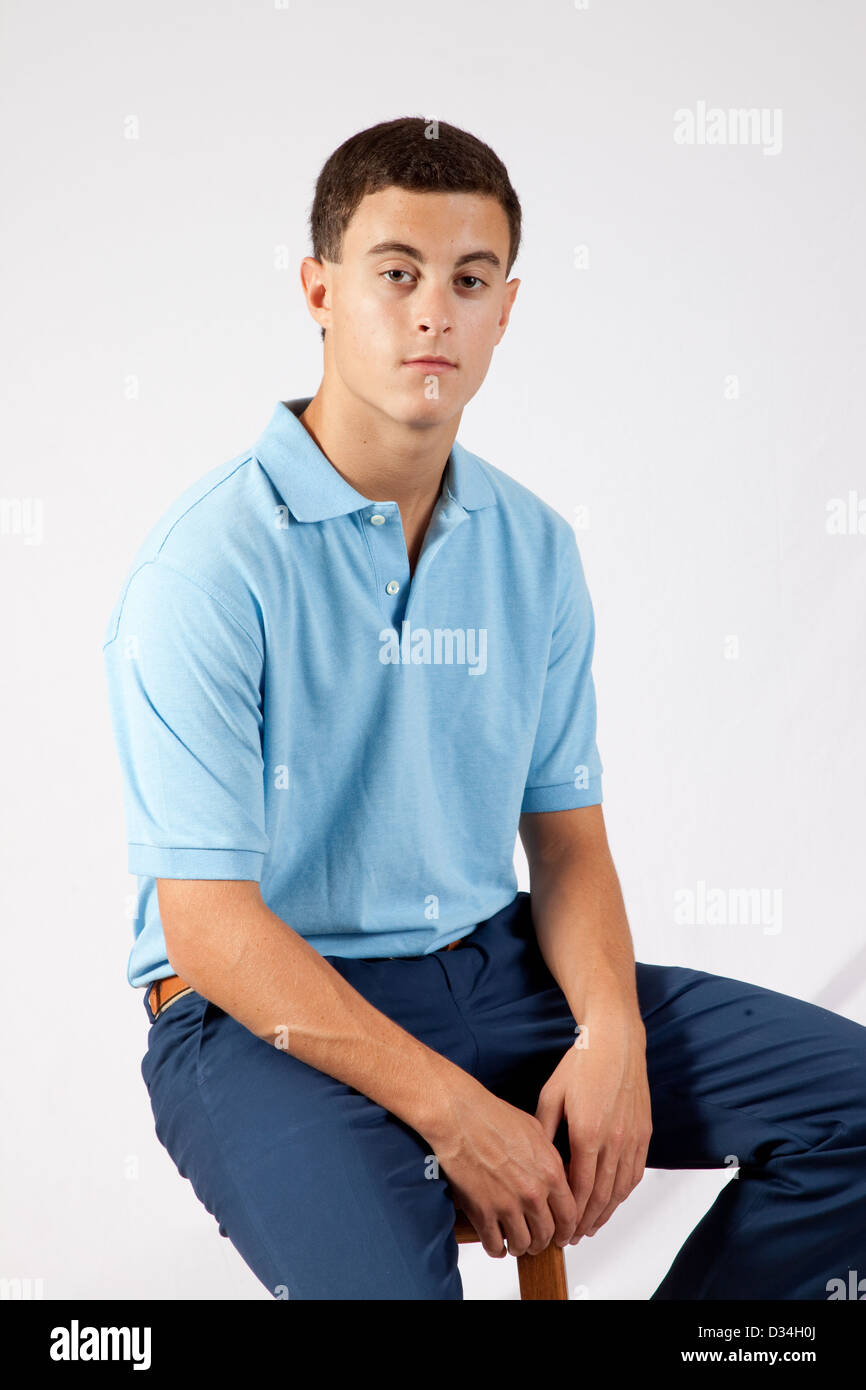Handsome white teenager in a blue shirt and dark blue slacks with a serious and thoughtful expression as he looks at the camera Stock Photo