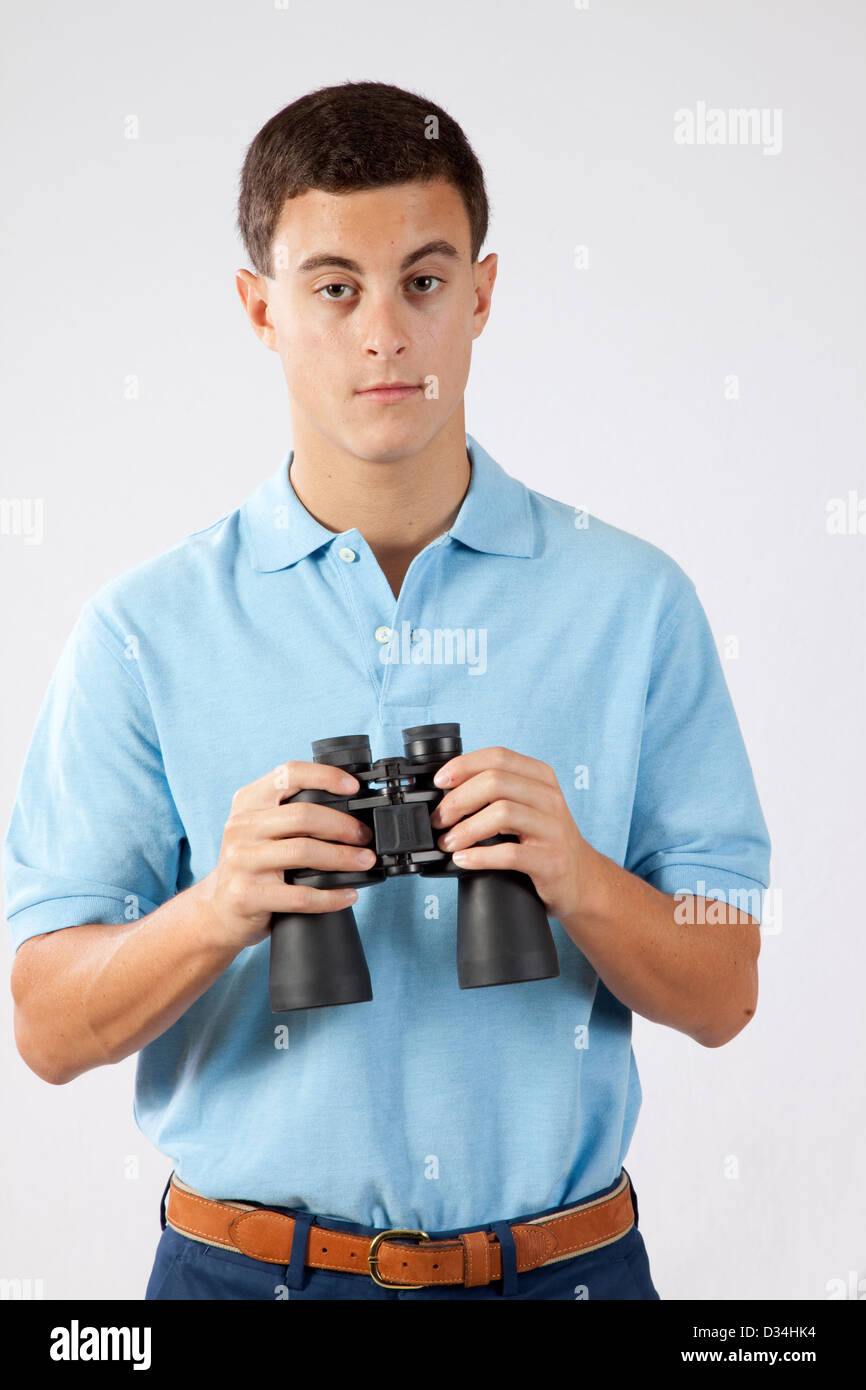Young man holding a pare of binoculars and looking at the camera with a ...
