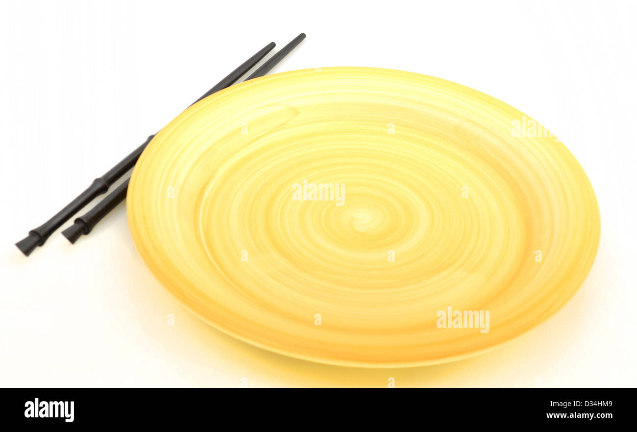 empty yellow plate with chopsticks for Asian cuisine Stock Photo