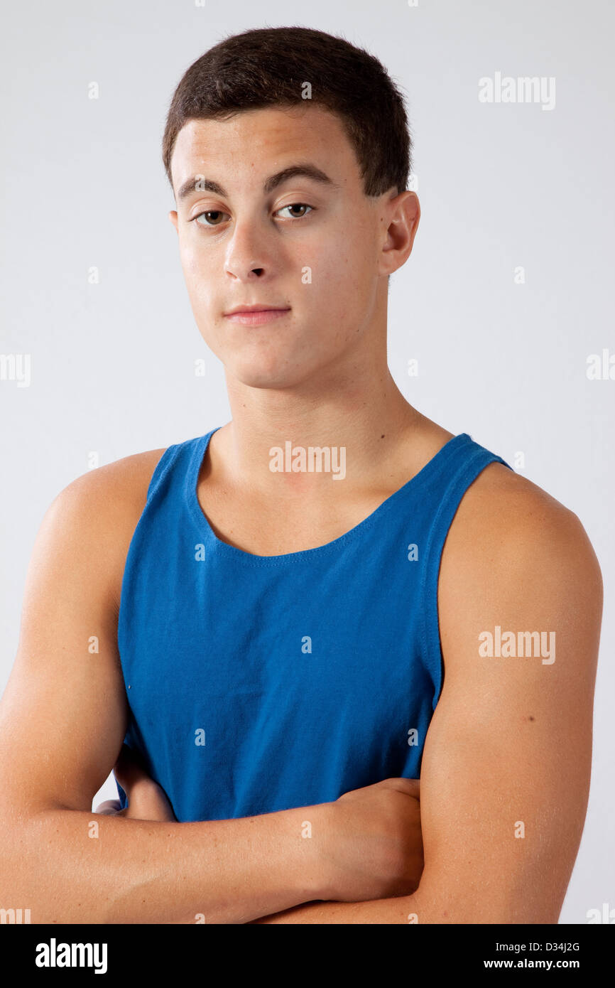 Handsome teenage boy in a blue tank top, standing with his arms crossed