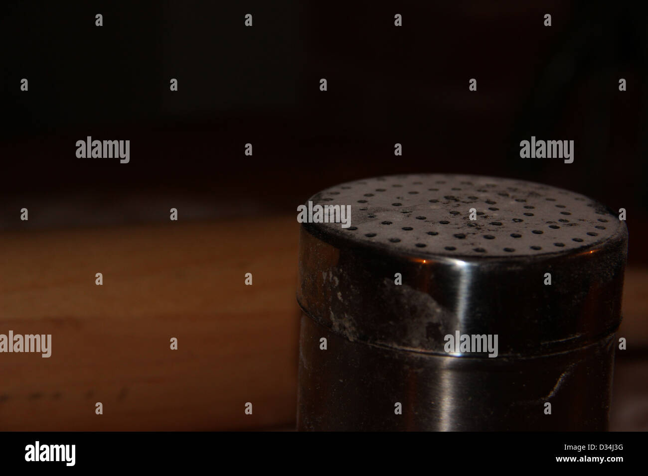 Closeup of a flour shaker in a country kitchen with wooden rolling pin in background Stock