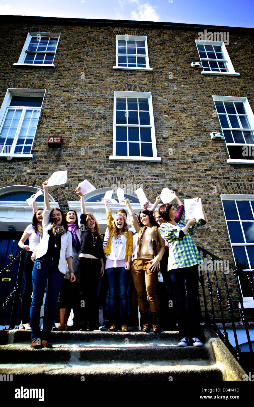 College class on the steps of a school with their diplomas in hand celebrating finishing college Stock Photo