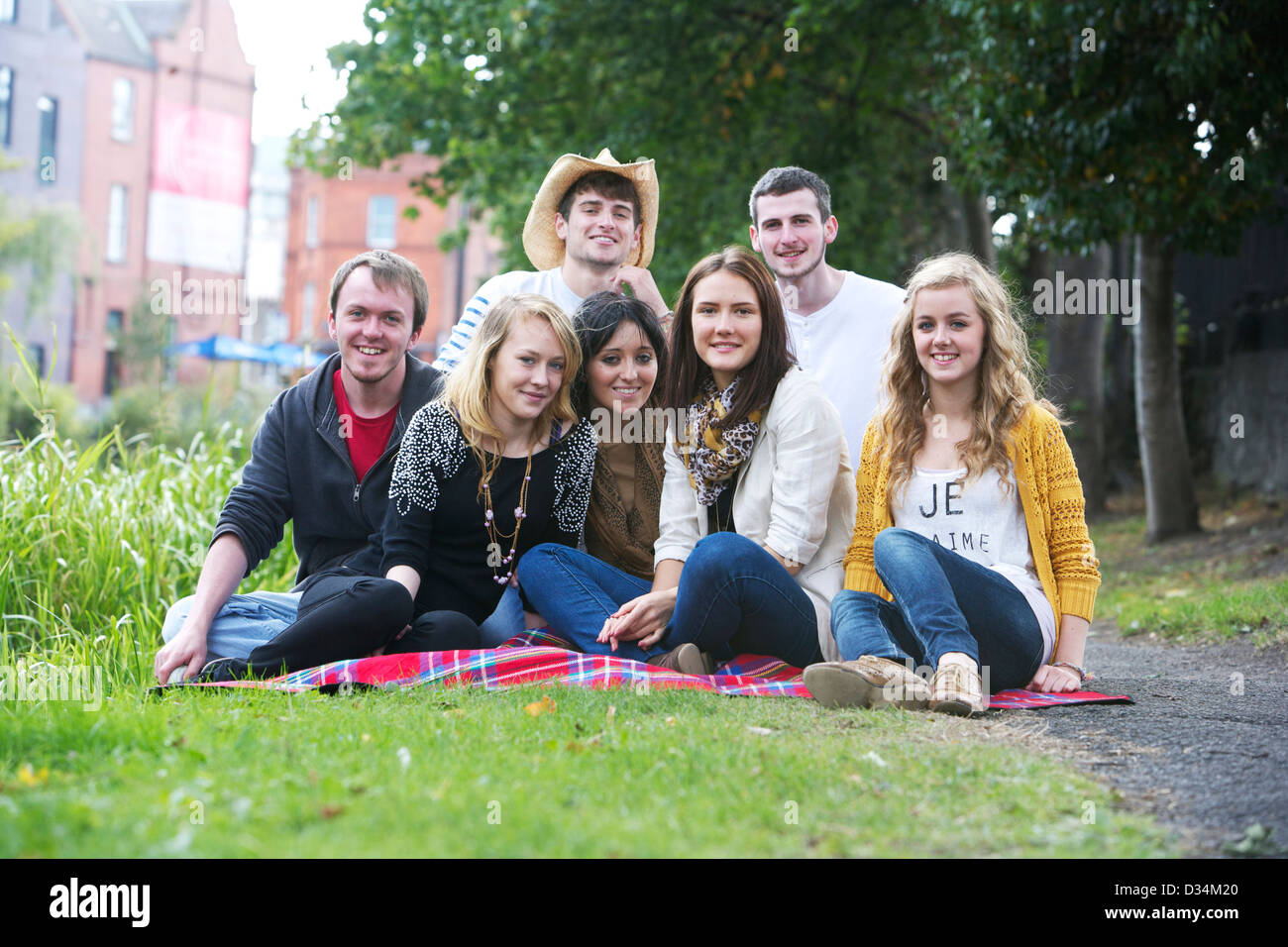 A group of young boys and girls sitting on picnic rug. Stock Photo