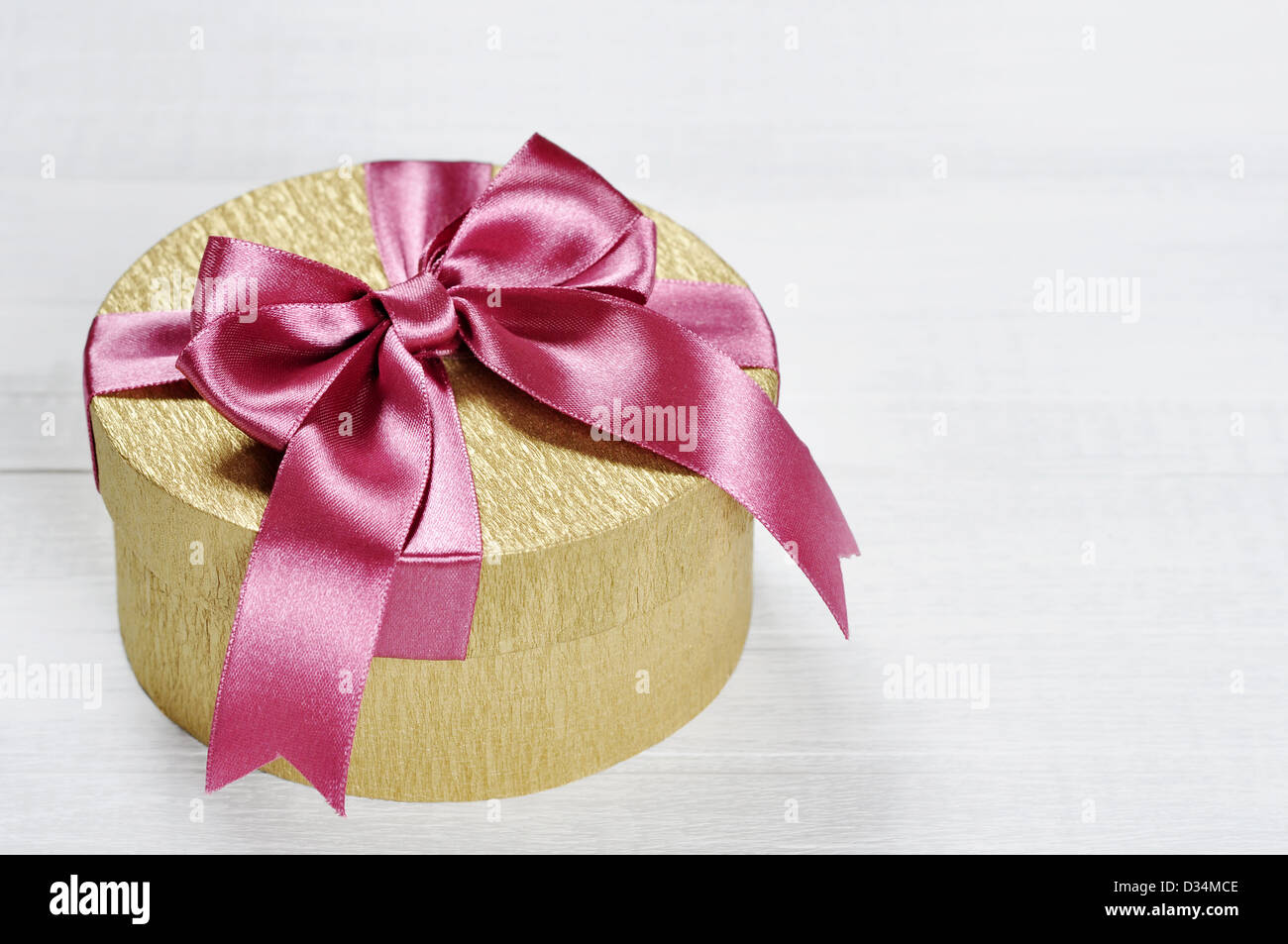 Golden gift box with pink ribbon on white wooden background Stock Photo ...