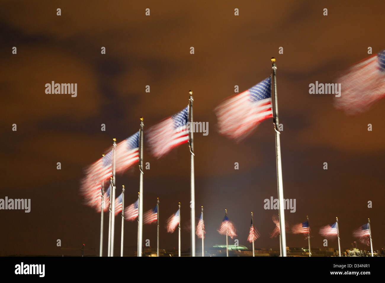 U.S. flags circle The Washington Monument on the mall at night, Washington DC Stock Photo