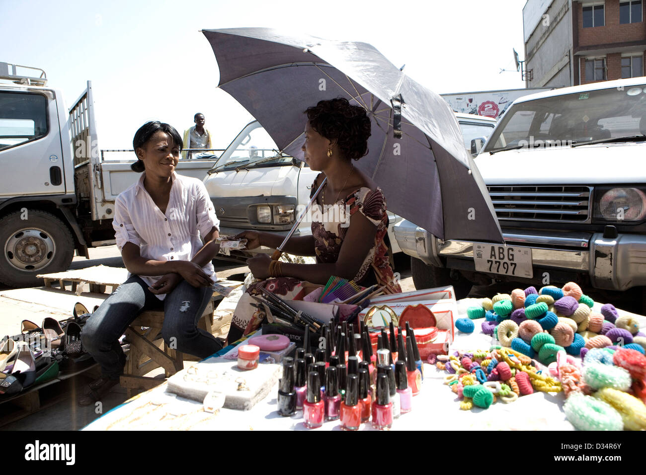 Two street vendors sitting and chatting in Lusaka City Market selling cosmetics Stock Photo